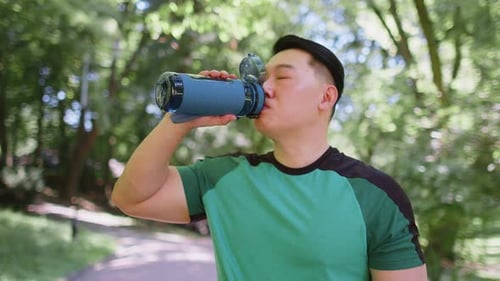 Sporty Athletic Thirsty Chinese Asian Sportsman Runner Jogger Drinking Water After Workout in Park