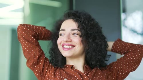 Close up portrait of a pretty smiling businesswoman resting while sitting in a modern office looking