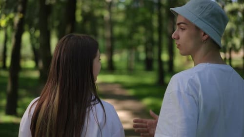 Slow Motion Rear View A Couple of Young People Talking to Each Other Walking in the Forest on a