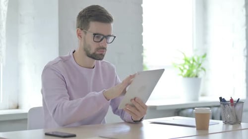 Man With Glasses Working on Tablet at Desk