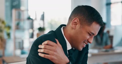 Man Rubs Shoulder in Office with Discomfort