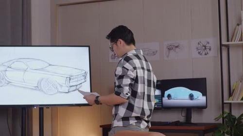 Designer Looking At Car Design Sketch Papers In His Hands And Walking Around In The Studio