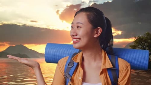 Close Up Of Asian Female Hiker Smiling And Pointing To Side At A Lake