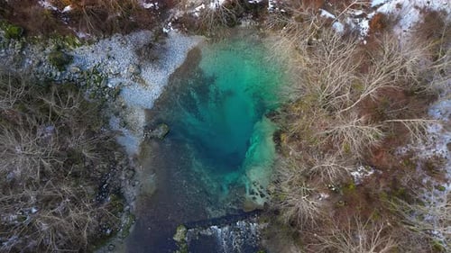 Die Drohne erhebt sich über einem kleinen, durchsichtigen türkisfarbenen Bergsee
