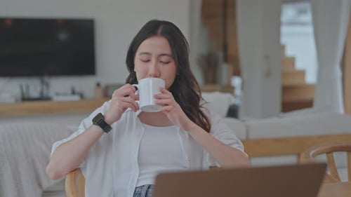 Asian woman drinking hot coffee from a white mug