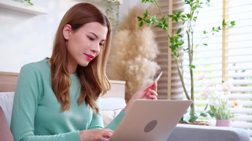Woman Using Laptop With Card at Home