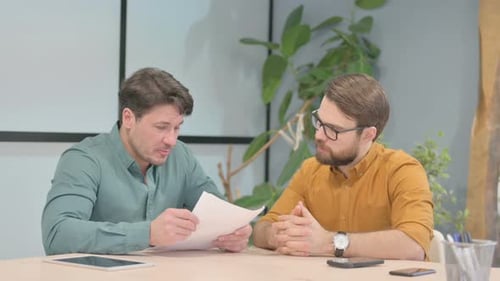 Men Discussing Business Documents in Office