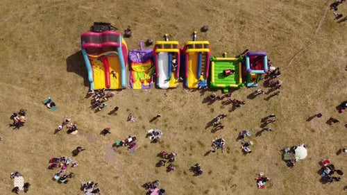 Colored inflatable slides and outdoor games for kids. Aerial top-down rising directly above