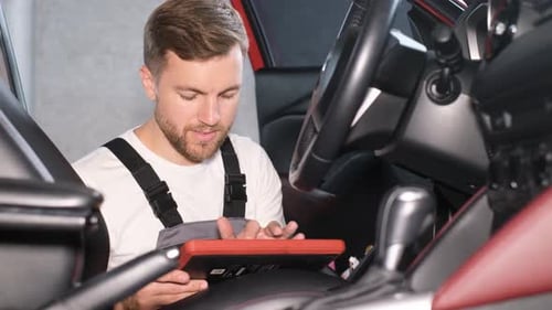 A Professional Car Mechanic Examines a Car at a Car Service Performing a Series of Tests