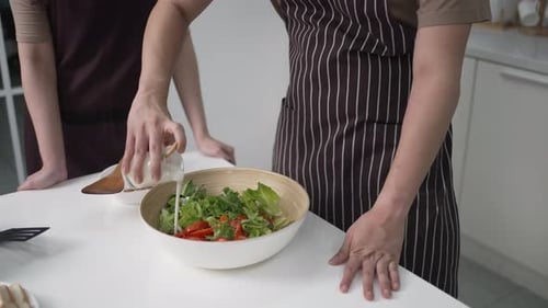 Adults Preparing a Fresh Salad in Kitchen