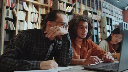Student Discussing Homework on Laptop with Group Mate in Library