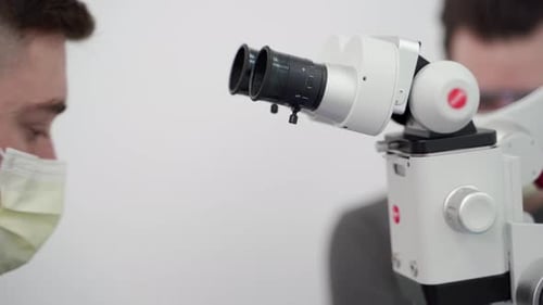 Odontólogo masculino que trabaja con un microscopio dental en una clínica de odontología moderna, endodoncista que busca