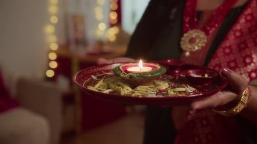Woman Holding Plate with Candle, Flower Petals