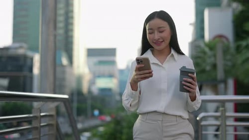 Business Woman Walking Outside Browsing in Cell Phone on Coffee Break Dressed In Business Clothes