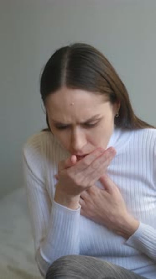Woman Coughing into Her Hand Indoors in a Home