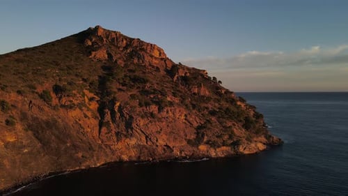 Drone footage of a seaside cliff along the coast of the Mediterranean Sea while beautifully lit by t