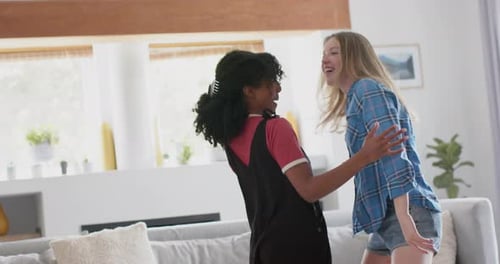 Happy diverse teenage female friends dancing at home, slow motion