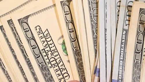 Bündel von einhundert US-Dollar-Scheinen in der Hand eines Mannes