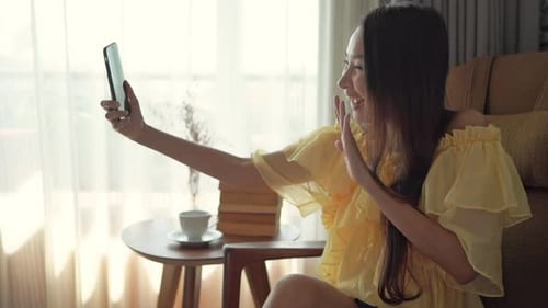 Woman Waving During a Video Call Indoors