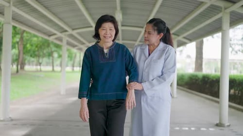 Doctor Helping Senior Woman Walking Outside
