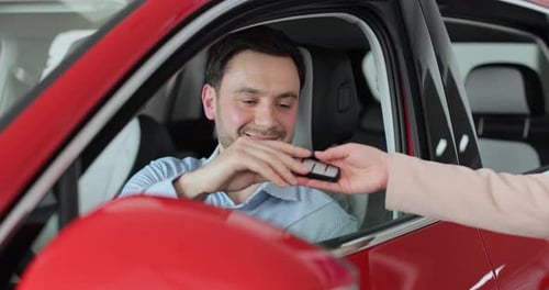 Sales Manager Handing Over the Keys to Man in the Car Young Man Showing Key to New Car Man Holding