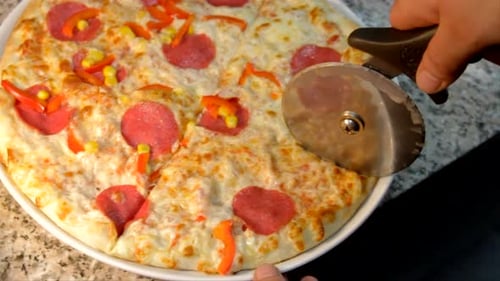 Fresh Pizza Being Cut Into Slices
