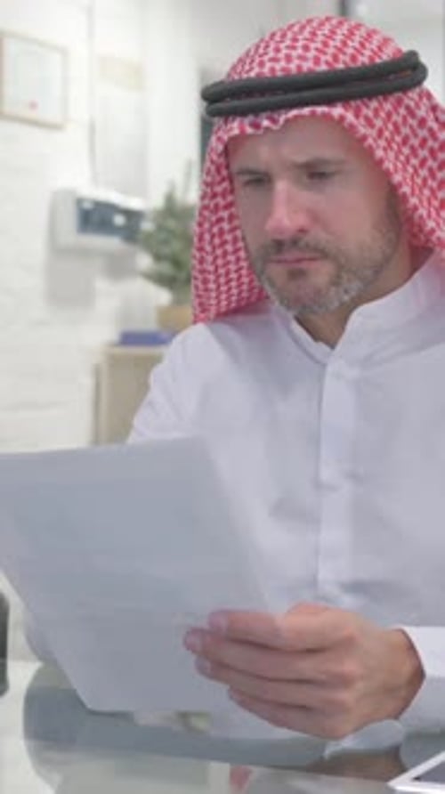 Man in Keffiyeh Reads Document in Office