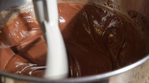 Close up shot of cake batter being blended with a paddle attachment on a stand mixer