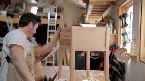 Carpenters Reviewing Paperwork Next to Side Table in Workshop 3539 Years