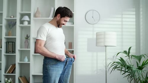 Happy handsome man feels joy after losing weight. Smiling satisfied middle aged bearded male tries