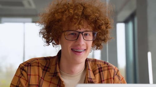 Young Adult with Red Hair Sits Indoors