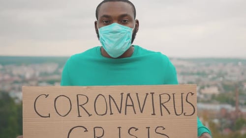 Adult Holding Coronavirus Crisis Sign Outdoors