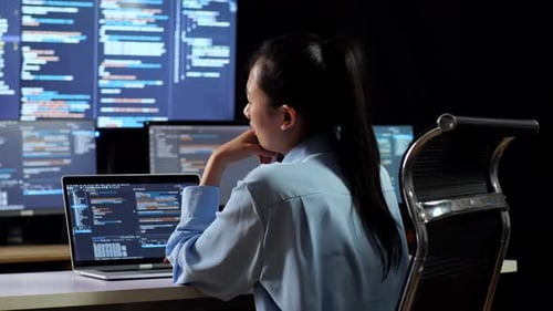 Back View Of Asian Female Programmer Thinking About Something While Writing Code By A Laptop