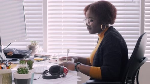 Young Creative Businesswoman Eating Lunch and Working at Desk in Office 2024 Years
