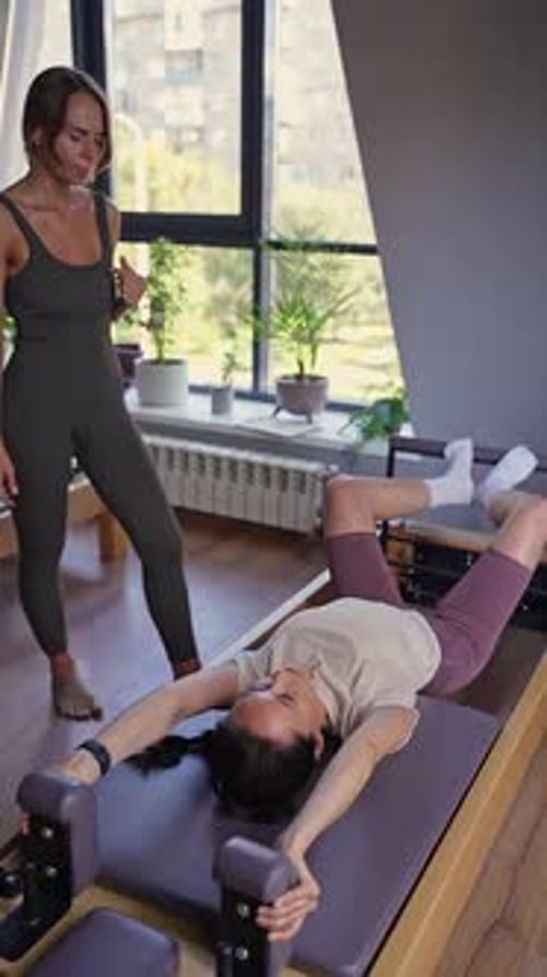 Women Exercising Pilates on Pilates Machine in Room