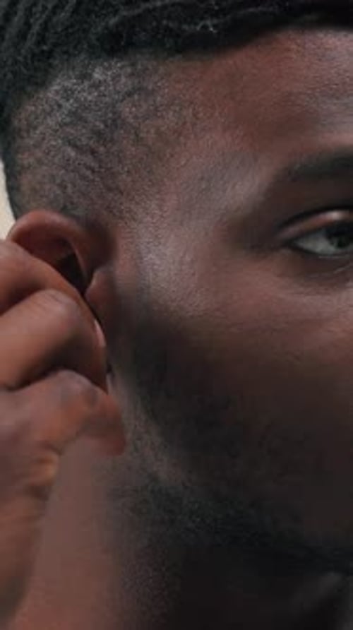Young Man Inserting Wireless Earbud in Ear