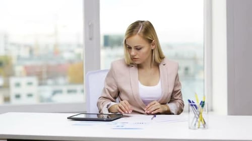 Woman works on tablet and writes at desk