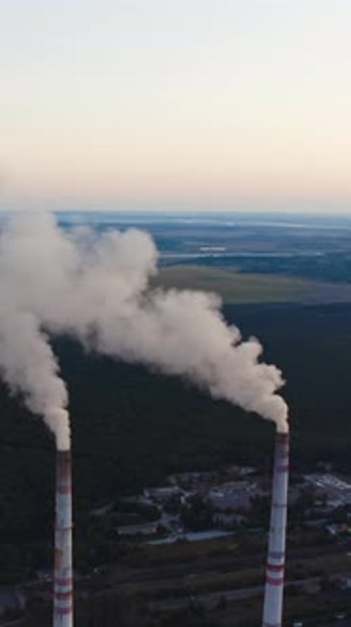 View of pipes with smoke. Power plant with white smoke over blue sky Vertical video