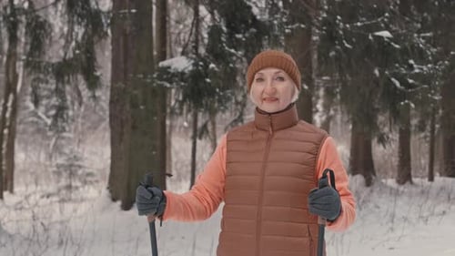 Portrait of Senior Woman with Walking Poles in Winter Forest