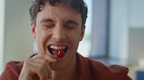 Man Enjoys Eating a Cherry Indoors