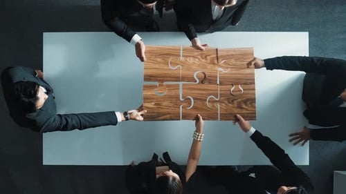 Team Solves Jigsaw Puzzle Together Above Office Table