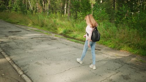 Lady Walking Thoughtfully Along Forest Road with Backpack