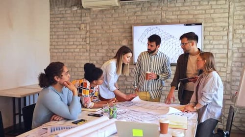 Group of young business people discussing architectural designs in office.