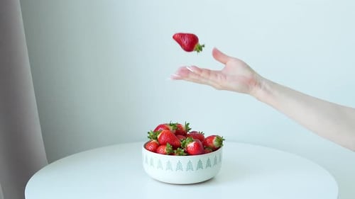 Hand Selecting Ripe Strawberries From Bowl on Table