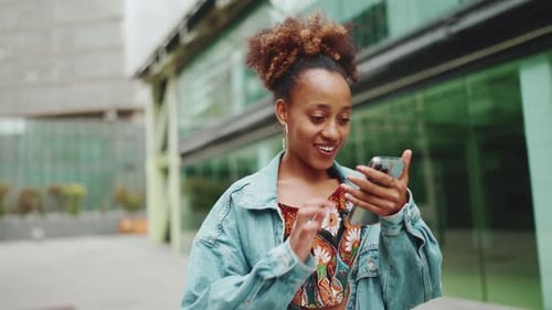 Cute girl walking down the street with phone in her hand