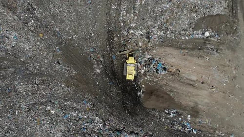 Bulldozer pushing garbage on a landfill - aerial view