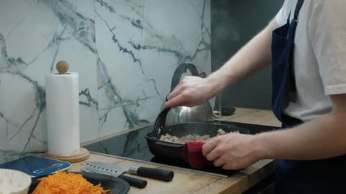Man Cooks Ground Meat in Kitchen Frying Pan