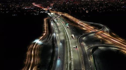 Aerial flyover traffic jam interchange road at night, drone shot top down view roadway intersection