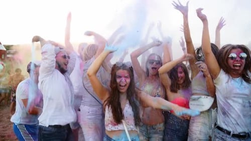 Jumping and Dancing Young People Have Fun and Throw Dry Colors Up in the Air at Holi Festival in