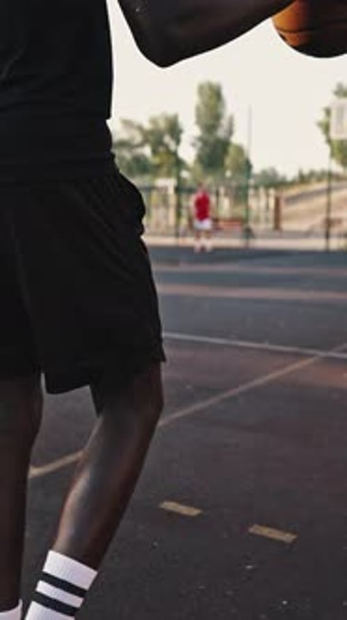 Rückansicht eines schwarzen Basketballspielers, der den Ball über das Feld dribbelt Männlicher Athlet trainiert weiter